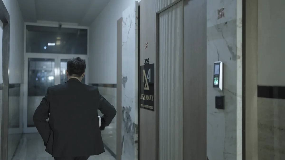 Simir walks down a building corridor at night