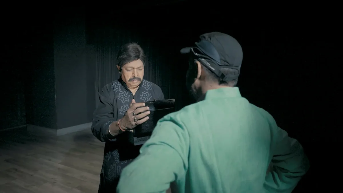Yash Kirti on a dark stage, holding a black frame